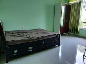 Ein Zimmer mit einem Bett, einem Kleiderschrank und einem Vorhangfenster.