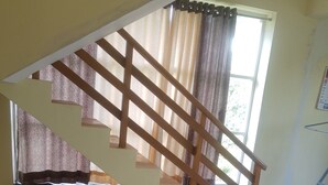 A staircase with wooden railings and a window with curtains.