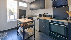 Een moderne keuken met donkere kastjes, een ingebouwde oven en een koffiezetapparaat.