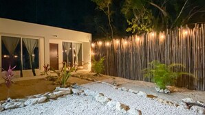 A modern house with a gravel pathway, a wooden fence, and a small garden with plants.