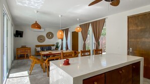 A modern kitchen with a large island, wooden furniture, and pendant lighting.