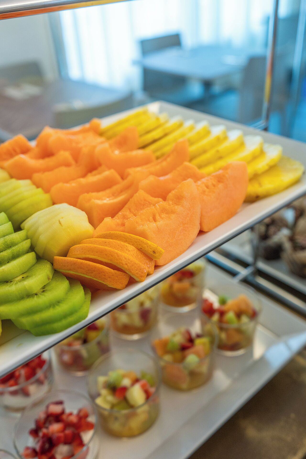 Una bandeja con una exhibición de frutas, kiwi en rodajas, melón y limón.