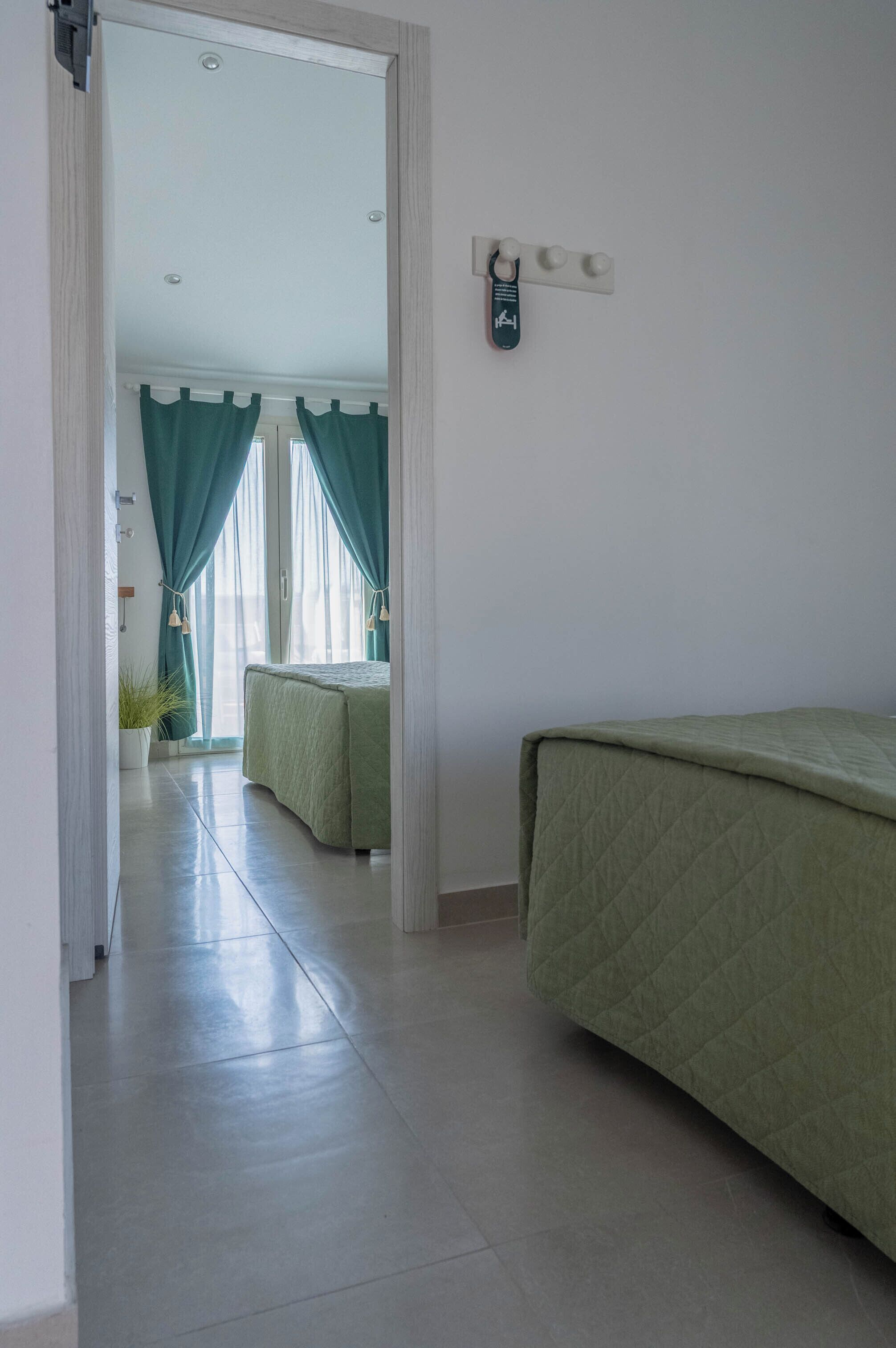 A hotel room with a bed, a small table, and a window with curtains.