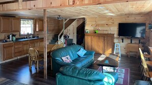 Ein Holzblockhaus mit Wohnzimmer, Küche und Essbereich.