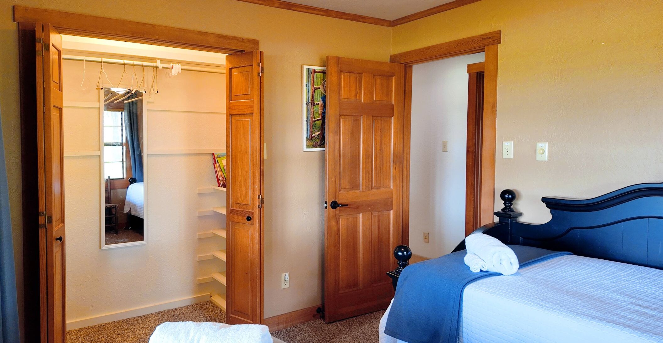 Un dormitorio con cama, una puerta de madera, un armario y una ventana.