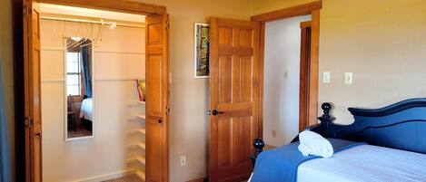 Un dormitorio con cama, una puerta de madera, un armario y una ventana.