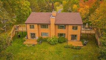 A two-story house with a deck, a garage, and a well-maintained lawn.