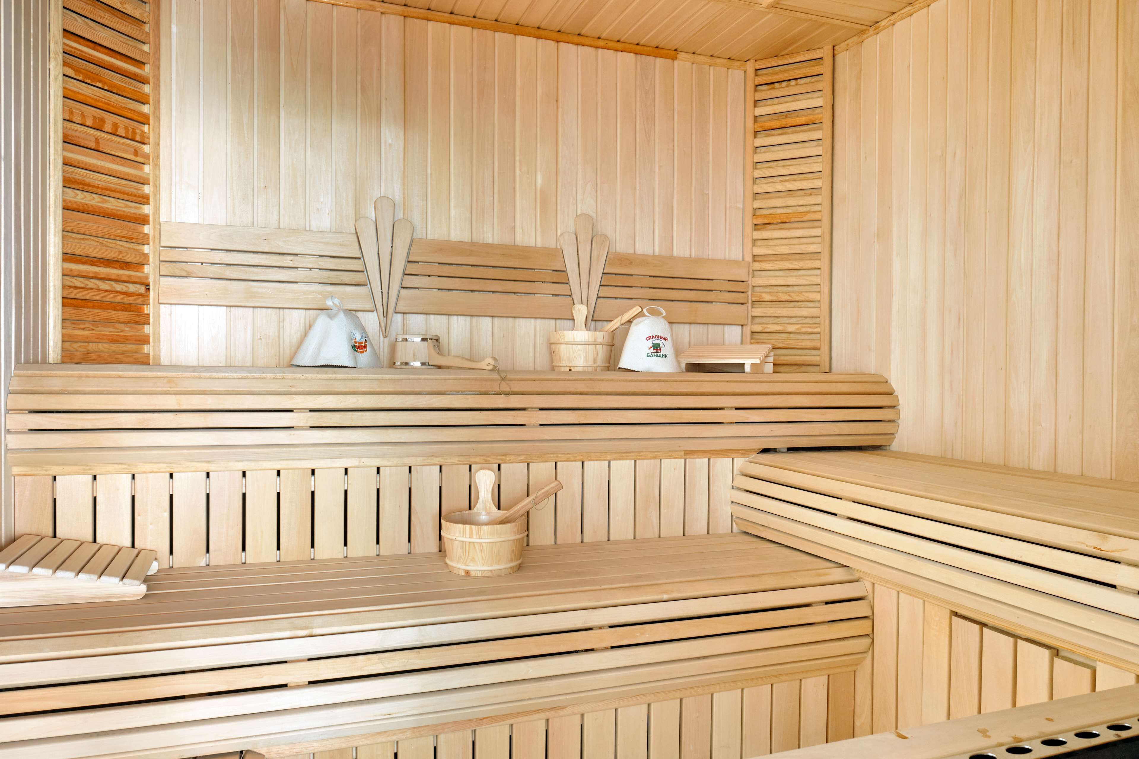Una sauna con bancos de madera y una pared de madera. Hay cucharas de madera y una bolsa sobre los bancos.