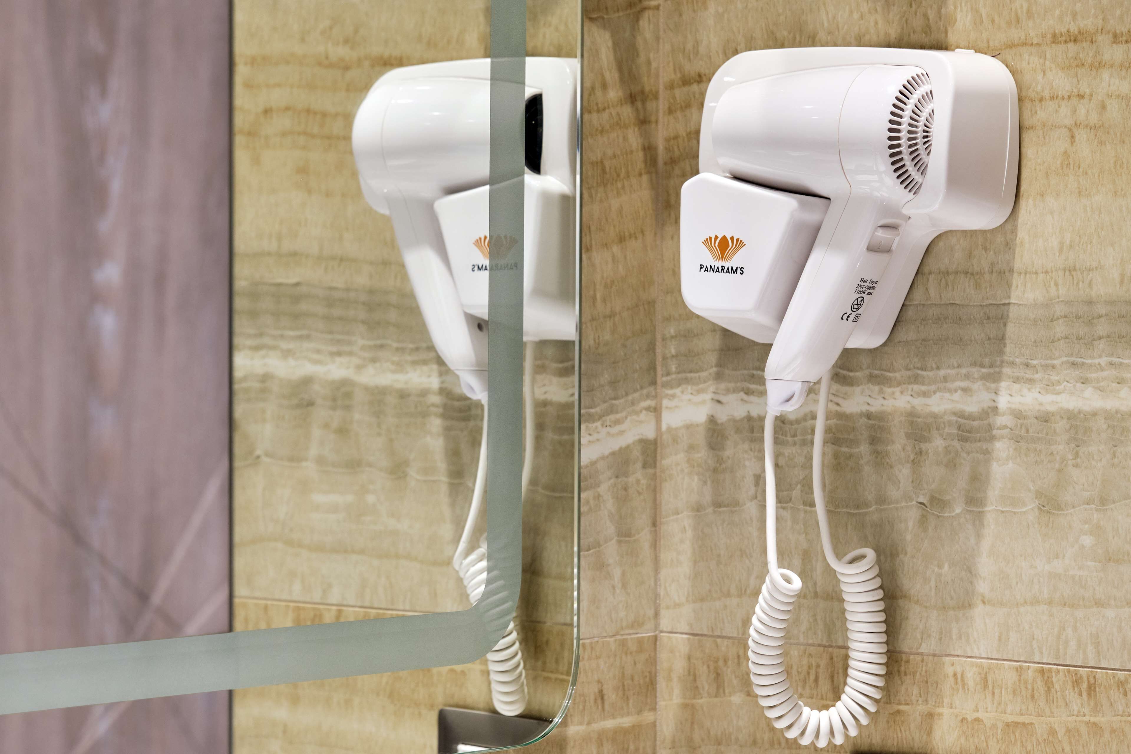 Ein an der Wand befestigter Föhn mit aufgewickeltem Kabel.