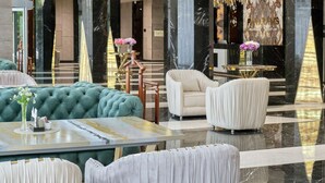 A lobby with a green tufted sofa, a marble reception desk, and a large marble wall with the word "PIRAMIDS" visible. - Panarams Tashkent Hotel, A member of Radisson Individuals (Tashkent)