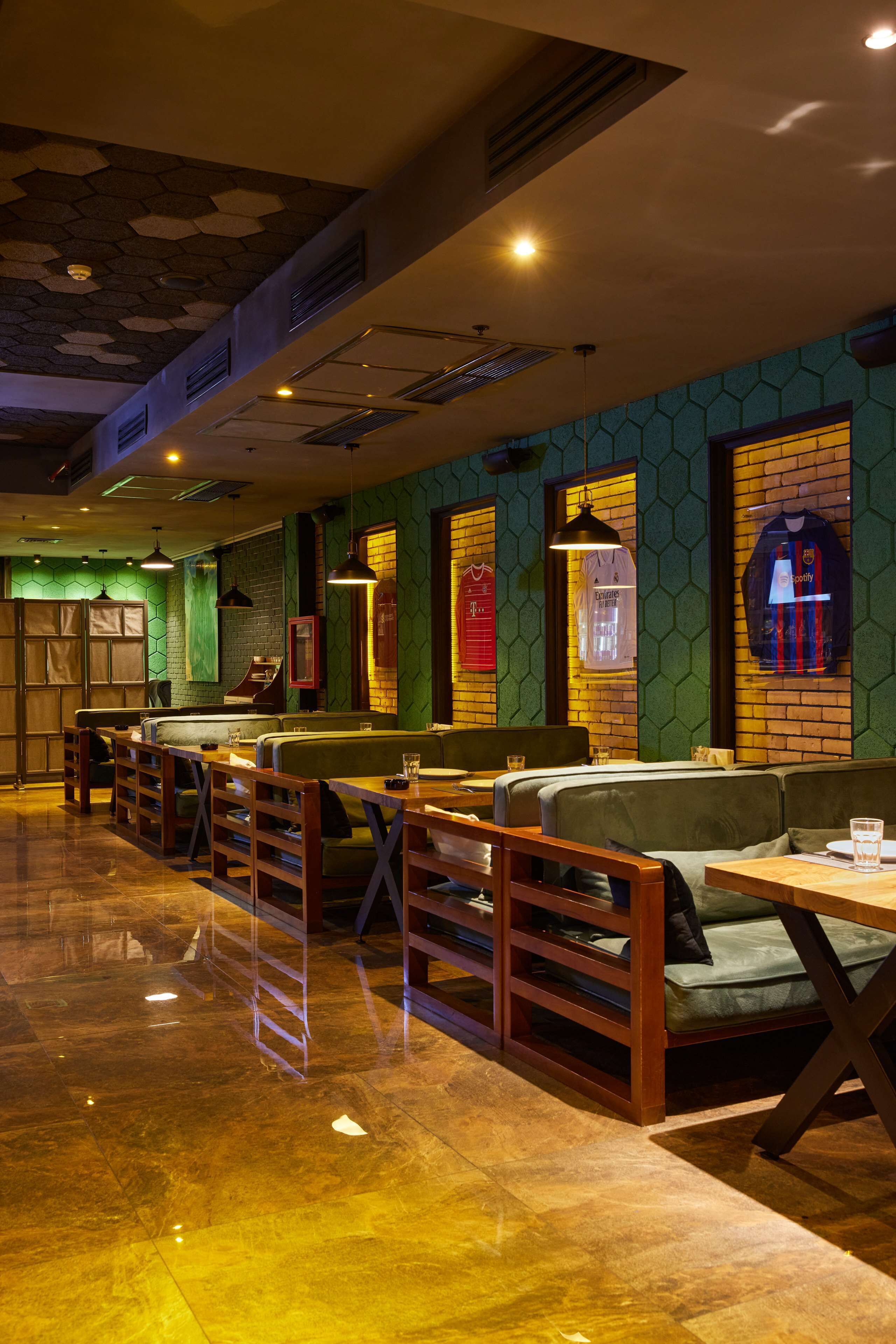Een restaurantinterieur met zitjes, tafels en een groen behang.