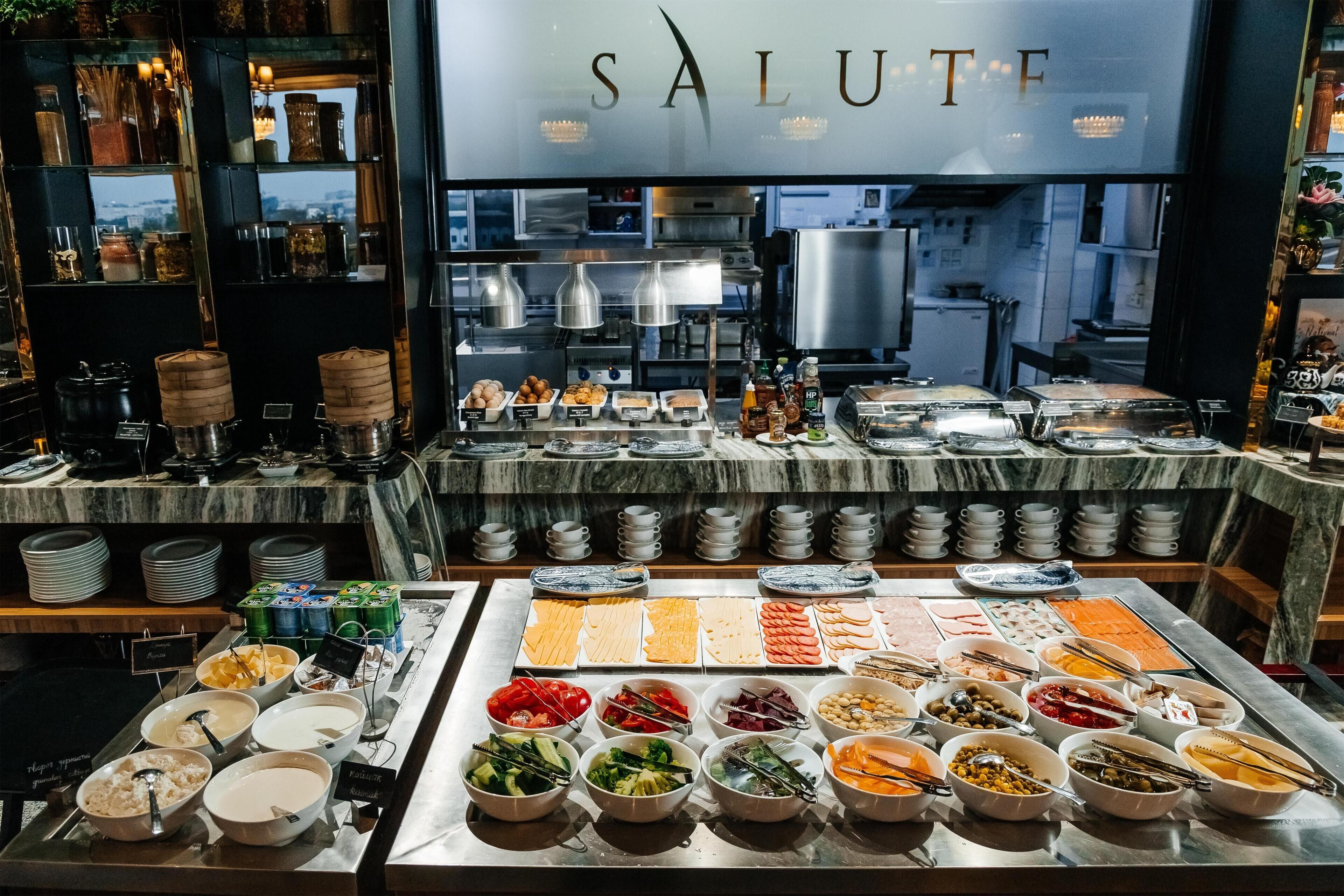 A buffet with various food options and a kitchen in the background.