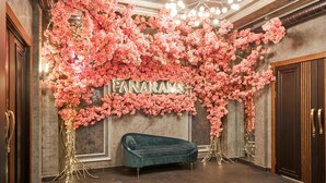 Une chambre luxueuse avec un canapé vert foncé, un lustre et un mur décoré de fleurs roses et du mot « PANARAMS ».