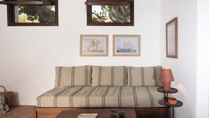 Ein gemütliches Wohnzimmer mit einem gestreiften Sofa, einem kleinen Holztisch und zwei gerahmten Bildern von Segelbooten an der Wand.