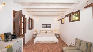 Ein Schlafzimmer mit einem Bett, Nachttischlampen, einem Holzschrank, einer Kaffeemaschine und einem kleinen Tisch mit Lampe.