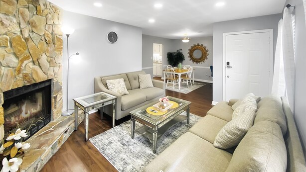 A living room with a stone fireplace, a sofa, a coffee table, and a dining area with a table and chairs. - NEW! Renovated Home - 10 Min to Augusta Downtown! (Evans)