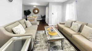 A living room with two sofas, a coffee table, and a dining area with a chandelier. - NEW! Renovated Home - 10 Min to Augusta Downtown! (Evans)