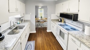 A modern kitchen with white cabinets, granite countertops, a built-in microwave, and a stove. - NEW! Renovated Home - 10 Min to Augusta Downtown! (Evans)