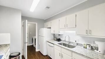 A modern kitchen with white cabinets, a stainless steel sink, and a built-in dishwasher.
