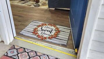 A living room with a stone fireplace, a blue door, and a welcome mat.