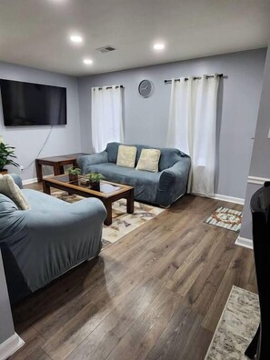 Una sala de estar con sofá, mesa de centro y cortinas.