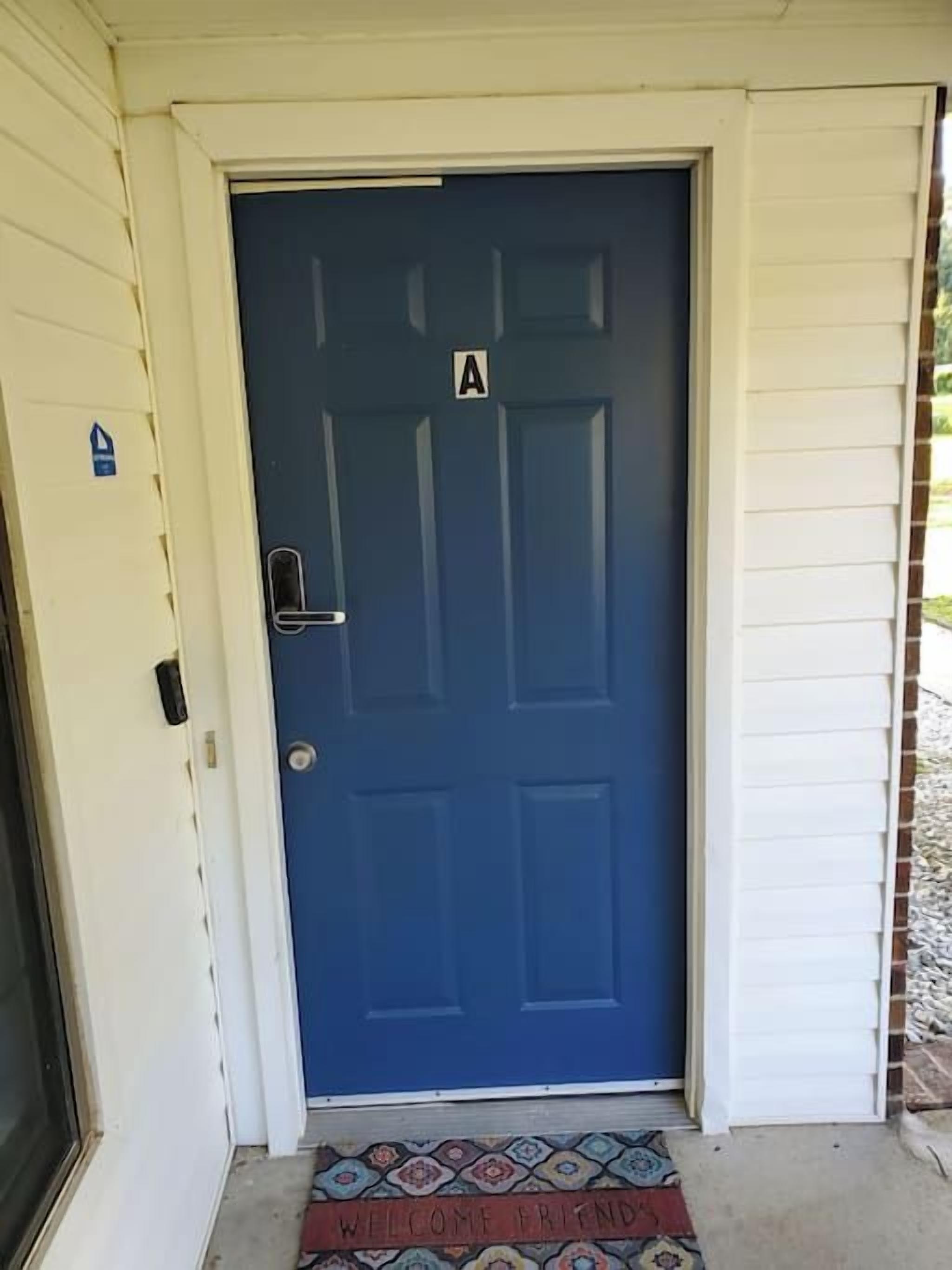 A blue door with a welcome mat and a sign indicating room number A.
