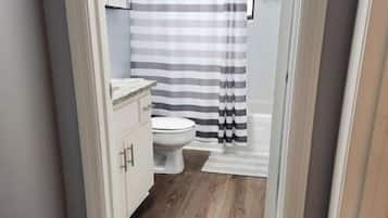 A narrow bathroom with a shower curtain, a toilet, and a cabinet.