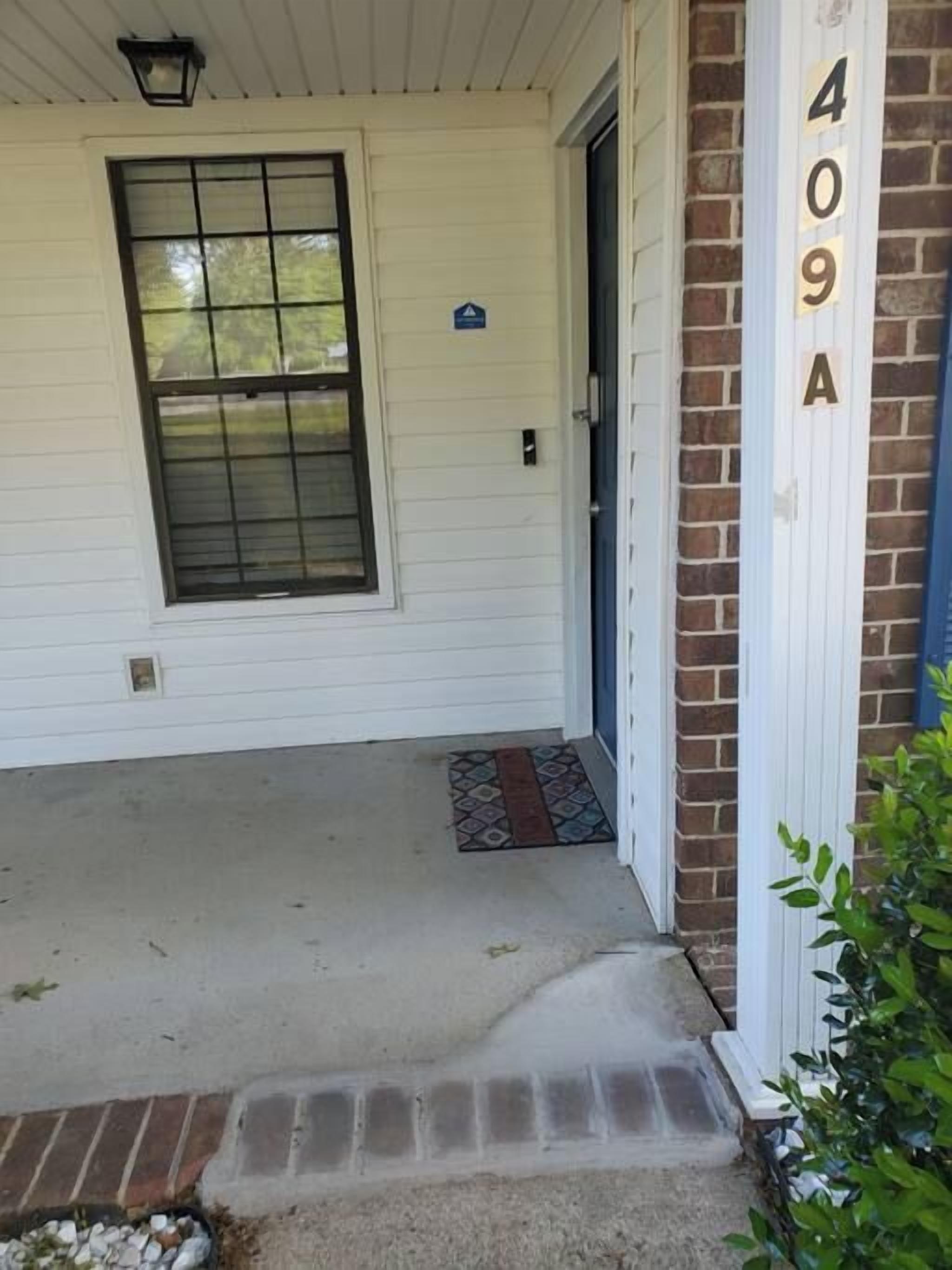 A house entrance with a door, a window, and a brick wall with the number 409A visible.