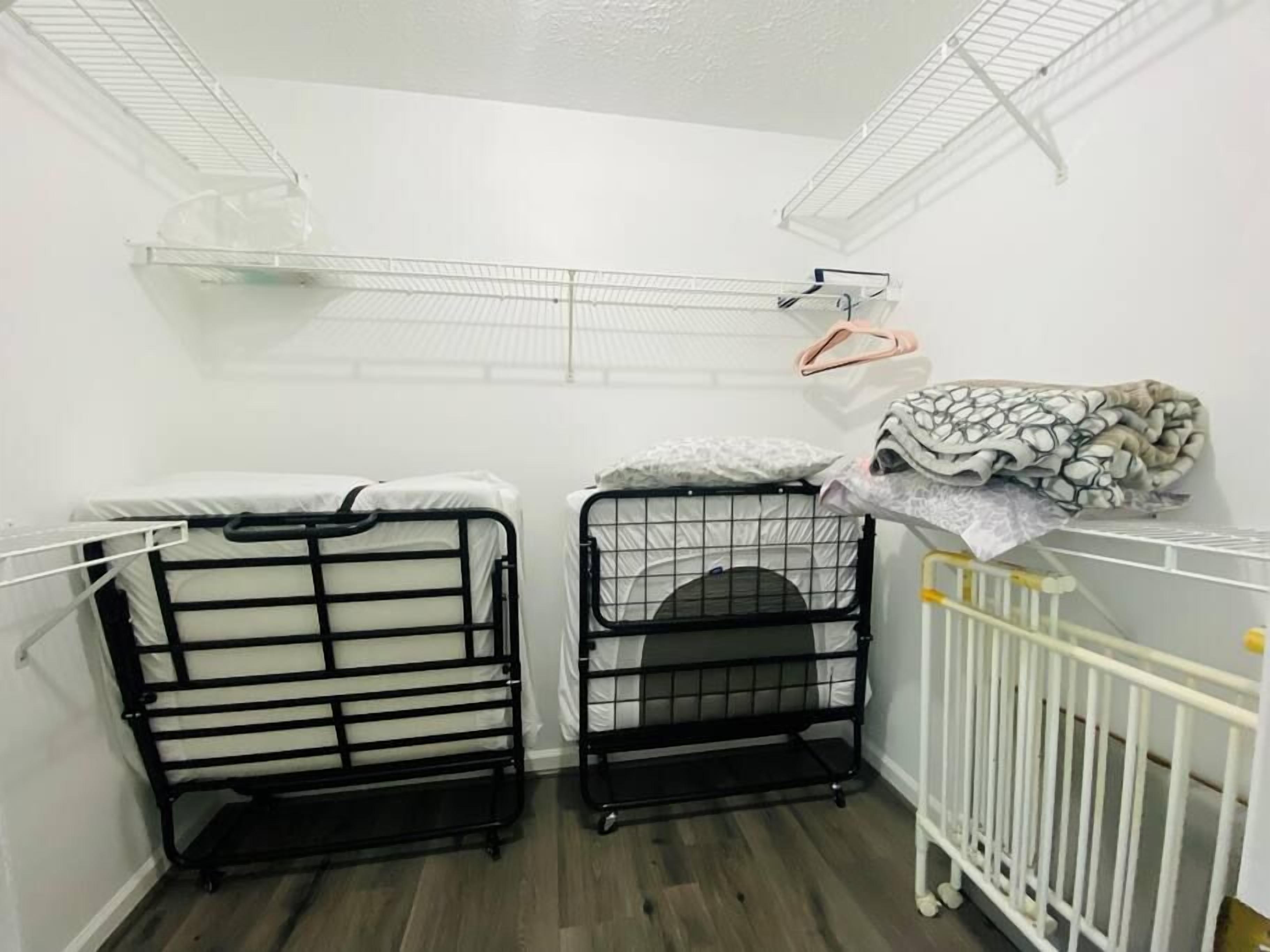 A room with bunk beds, a crib, and storage shelves.