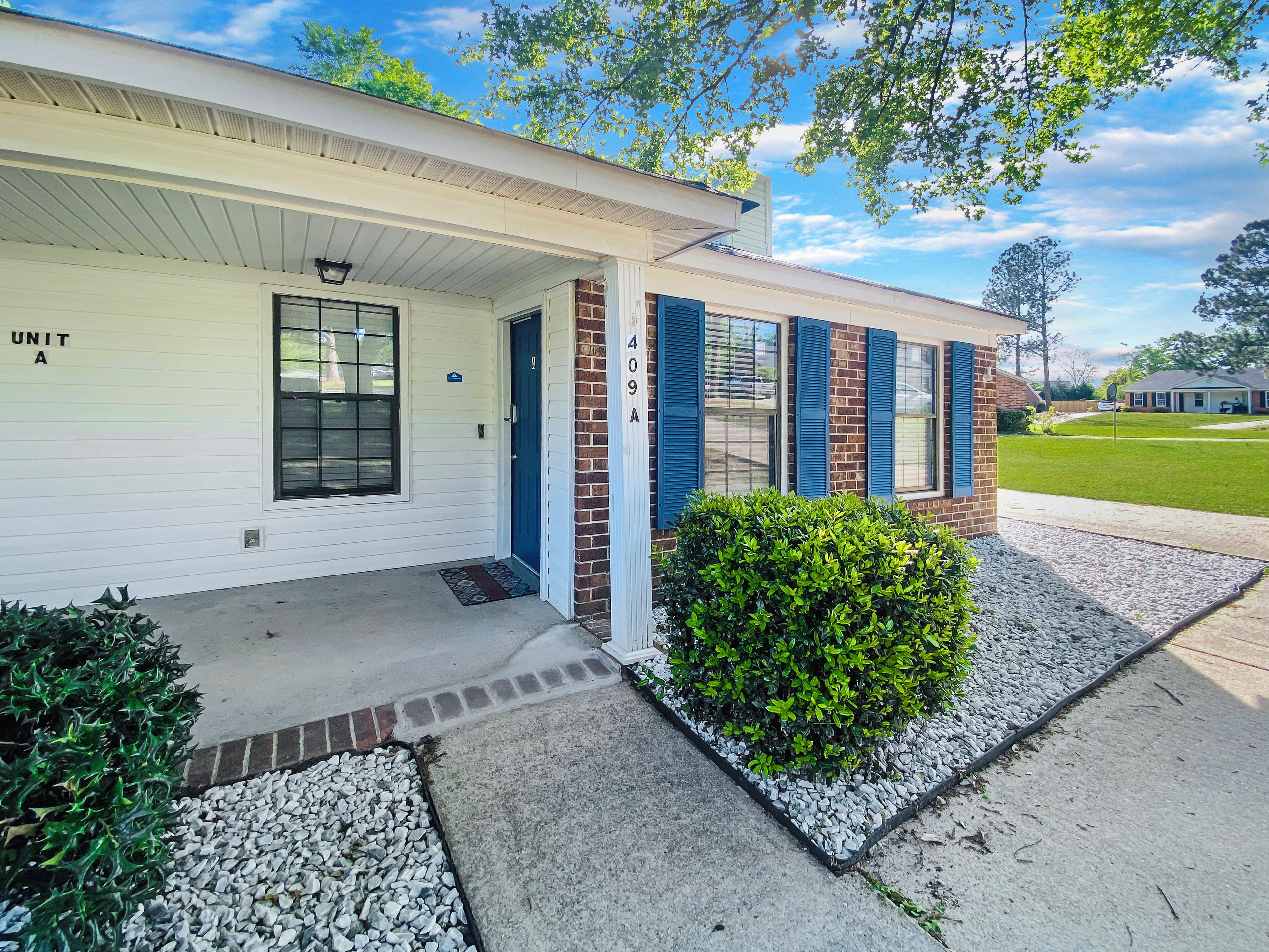 A two-story building with a white exterior, blue shutters, and a small front porch.
