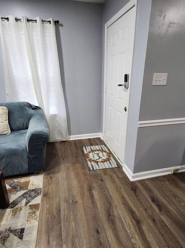 A room with a blue couch, a white door, and a patterned rug on a wooden floor.