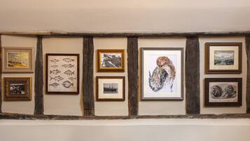 A wall with framed artwork including fish illustrations, a photograph of a person on a boat, and an owl.