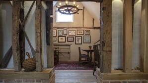 A rustic interior with exposed wooden beams, a chandelier, and a collection of framed artwork on the walls. - The Ferry Boat Inn (Chelmsford)