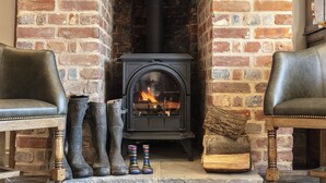 A rustic room with a brick fireplace, leather chairs, and vintage boots. - The Ferry Boat Inn (Chelmsford)