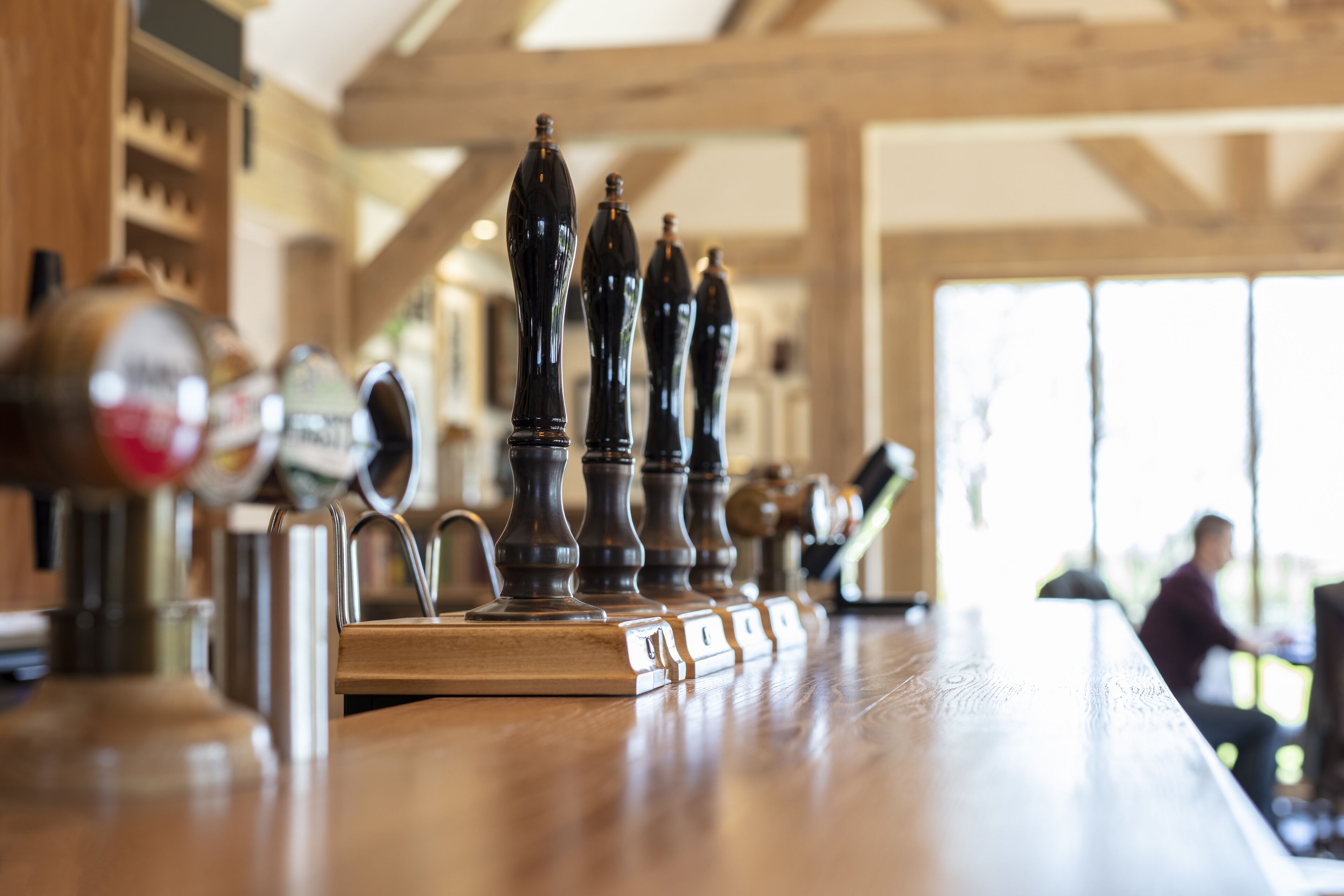 Una zona de bar con mostrador de madera y múltiples grifos de cerveza.