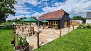 A wooden building with a tiled patio and outdoor seating area. - The Ferry Boat Inn (Chelmsford)