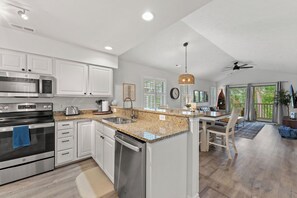 A modern kitchen with stainless steel appliances, a granite countertop, and a dining area with a view.