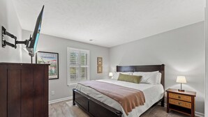 Una camera da letto con un letto, comodini, una cassettiera, una finestra con tende e una ventola a soffitto.