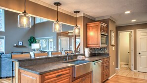 Una cocina moderna con armarios de madera, una isla grande e iluminación colgante.