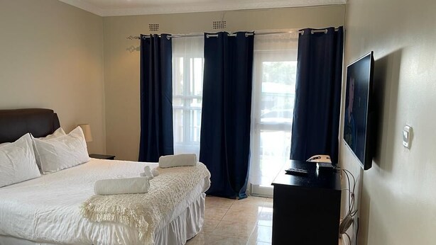 Habitación de hotel con una cama grande, un escritorio con computadora y un televisor montado en la pared.