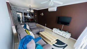 Una sala de estar moderna con un sofá seccional gris, una mesa de centro de madera y un televisor de pantalla plana montado en la pared.
