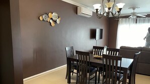 Un comedor con pared marrón oscuro, una araña y un ventilador de techo.