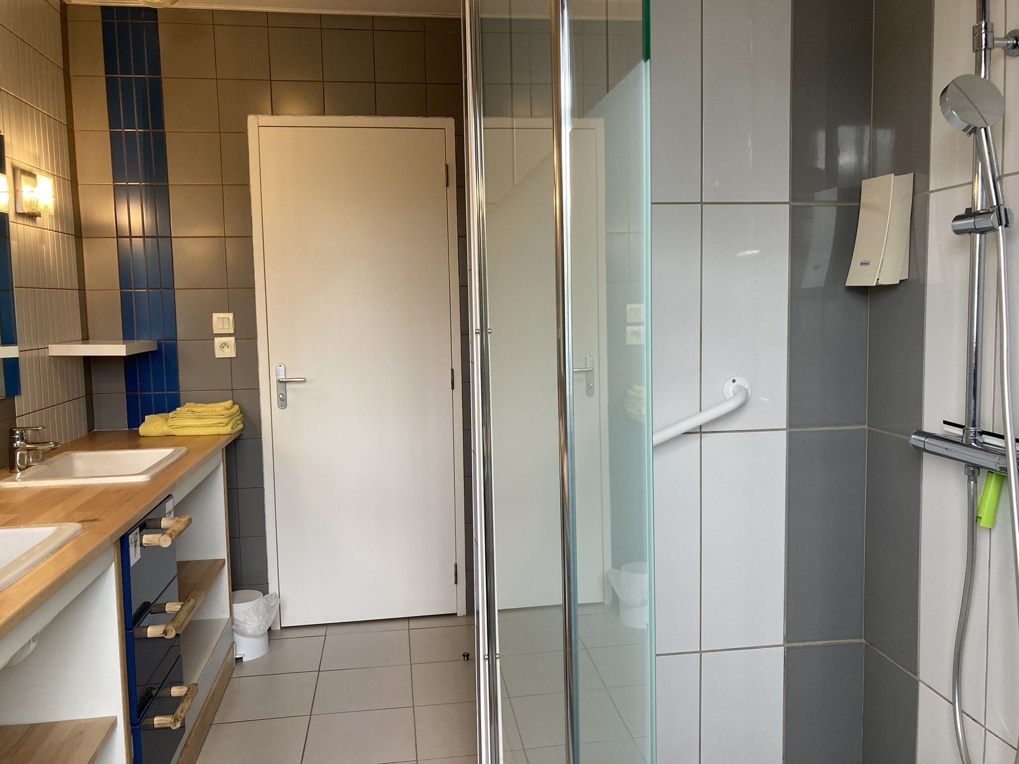 A modern bathroom with a glass shower enclosure, a white sink, and a wooden vanity.