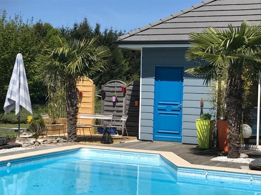Ein Swimmingpool mit einer blauen Tür und einer kleinen Gartenhütte im Hintergrund.