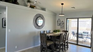 Un coin repas avec une table et des chaises en bois foncé, un miroir rond accroché au mur et un luminaire au plafond.