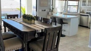 Une cuisine spacieuse dotée d’un grand îlot central, d’appareils électroménagers modernes et d’un coin repas avec une table et des chaises en bois.
