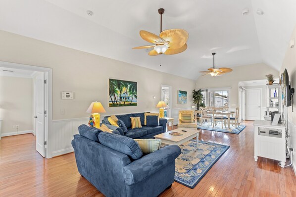 A spacious living room with a blue sofa, a coffee table, and a ceiling fan.