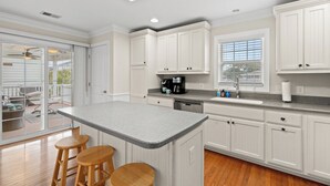 A kitchen with white cabinets, a gray countertop, and wooden stools. - No Shoes, No Shirt, No Problems at this 4 Bed/3 Bath Home with Hot Tub - Walk to Beach (North Myrtle Beach)