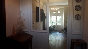 A hallway with a wooden floor, a door leading to a bright room, and a vase with dried flowers on a table. - Magnificent and large 18th century house, in a mountain village (Luz-Saint-Sauveur)