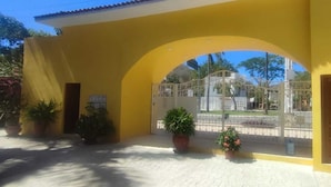 A yellow building with an arched entrance, potted plants, and a gated area with a view of a cemetery. - Nice condominium with lots of amenities. Huatulco (Crucecita)